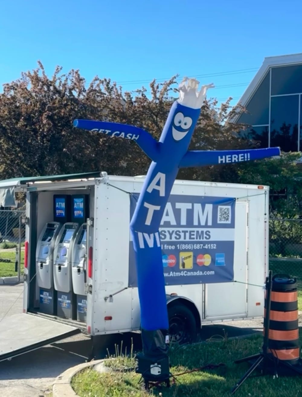 ATM Systems mobile trailer with two ATMs and a Get Cash Here inflatable tube dancer at an outdoor event